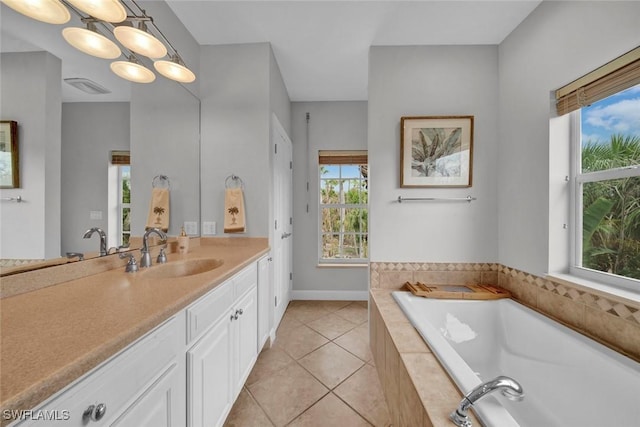 bathroom with a garden tub, visible vents, vanity, baseboards, and tile patterned floors