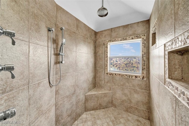 bathroom featuring vaulted ceiling and a tile shower