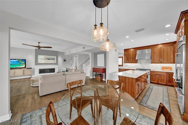 dining room featuring recessed lighting, visible vents, light wood-style flooring, stairway, and a glass covered fireplace