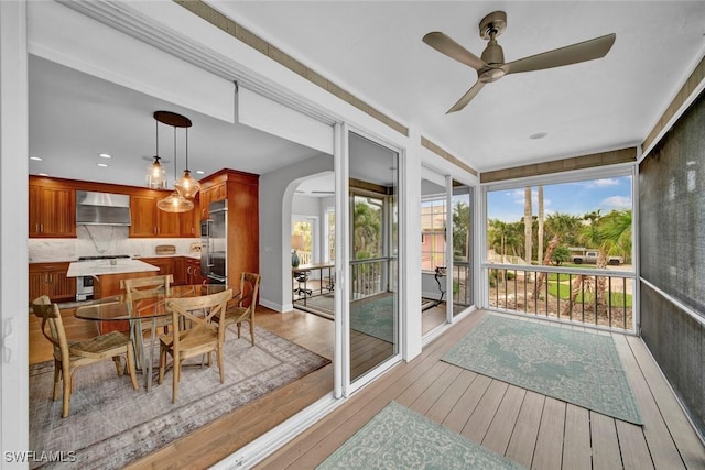 sunroom featuring arched walkways and a ceiling fan