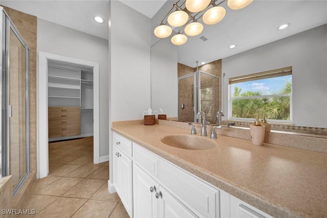 bathroom with visible vents, tile patterned flooring, a spacious closet, vanity, and a shower stall