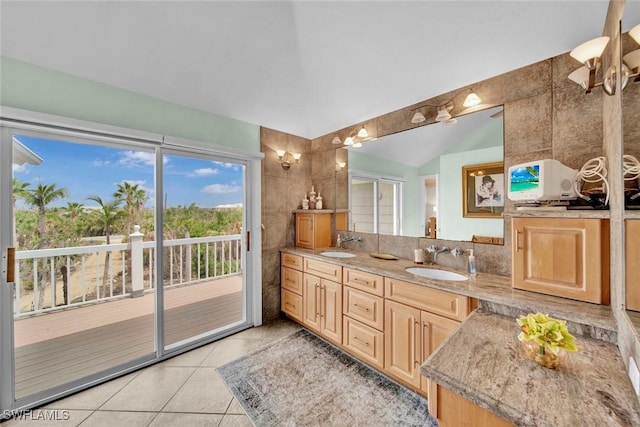 full bathroom with tile patterned flooring, vaulted ceiling, a sink, and double vanity