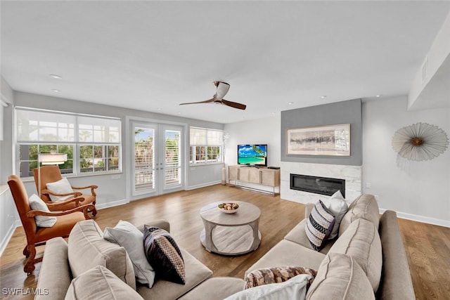 living room with baseboards, light wood-style flooring, a premium fireplace, french doors, and recessed lighting