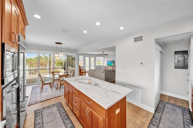 kitchen featuring a kitchen island, visible vents, brown cabinetry, and decorative light fixtures