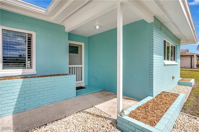 doorway to property featuring brick siding and stucco siding