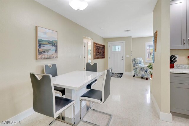 dining room featuring baseboards, visible vents, and light speckled floor