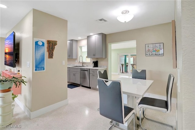 kitchen with visible vents, gray cabinets, light countertops, stainless steel dishwasher, and a sink