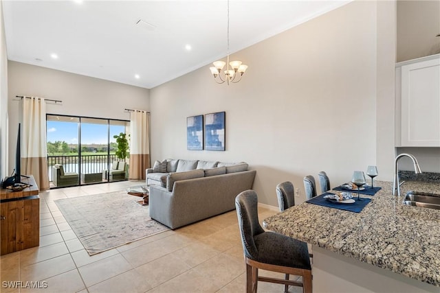 living area featuring a chandelier, light tile patterned flooring, a high ceiling, baseboards, and recessed lighting