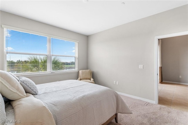 bedroom with baseboards and light colored carpet
