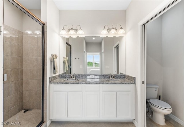 full bathroom with a sink, toilet, a stall shower, and double vanity