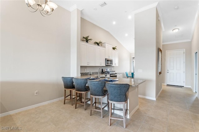 kitchen with a kitchen bar, visible vents, white cabinetry, stainless steel appliances, and crown molding