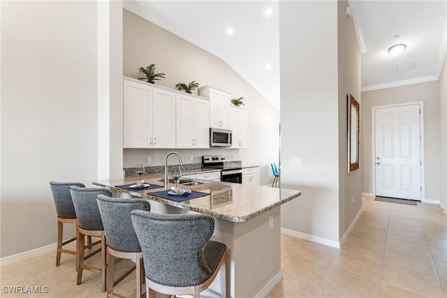 kitchen featuring a sink, light stone counters, white cabinetry, stainless steel appliances, and light tile patterned floors