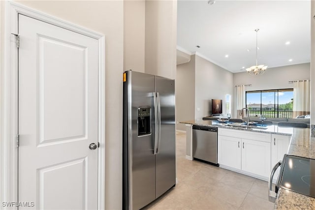 kitchen featuring a sink, appliances with stainless steel finishes, white cabinets, an inviting chandelier, and light stone countertops