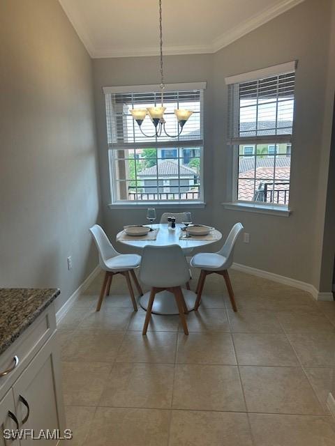 dining room with crown molding, a chandelier, baseboards, and light tile patterned floors