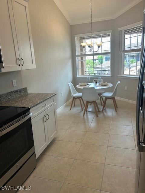 kitchen with stainless steel electric range, crown molding, a chandelier, baseboards, and white cabinets