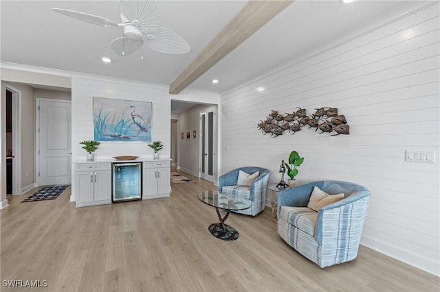 sitting room with beverage cooler, baseboards, beamed ceiling, and light wood finished floors