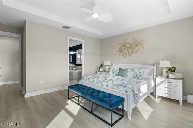 bedroom featuring visible vents, a raised ceiling, light wood-style flooring, and baseboards