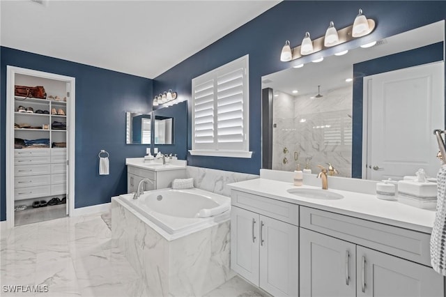 bathroom with marble finish floor, two vanities, a spacious closet, a stall shower, and a sink