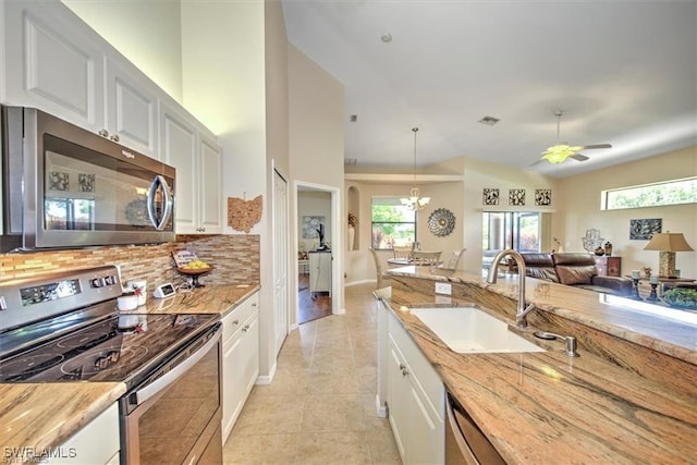 kitchen with stainless steel appliances, a sink, white cabinets, wooden counters, and pendant lighting