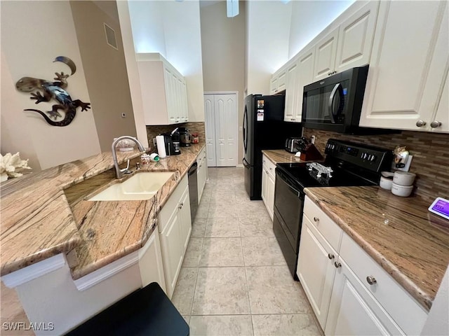 kitchen with white cabinets, a sink, light stone countertops, a peninsula, and black appliances