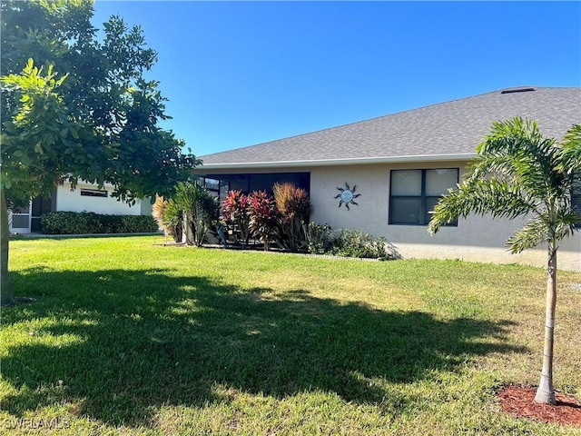 view of front of house featuring a shingled roof, a front lawn, and stucco siding