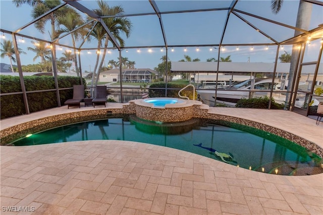 outdoor pool featuring an in ground hot tub, a patio area, and a lanai