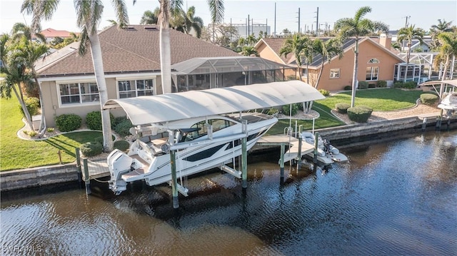 dock area featuring a lanai, a water view, a lawn, and boat lift