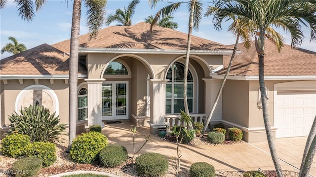 mediterranean / spanish-style home with a garage, roof with shingles, french doors, and stucco siding