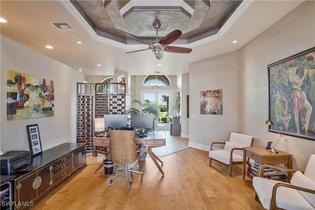 office area featuring light wood-type flooring, a tray ceiling, visible vents, and crown molding