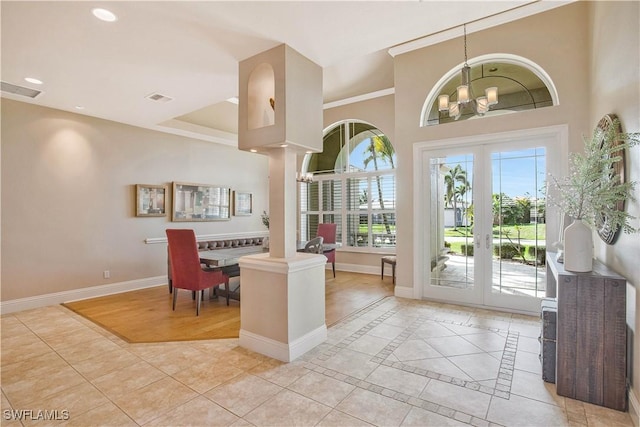 entrance foyer featuring ornate columns, visible vents, a notable chandelier, and baseboards