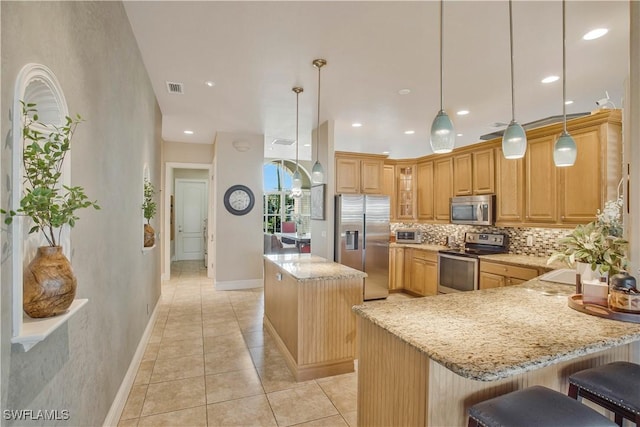 kitchen with hanging light fixtures, a kitchen bar, appliances with stainless steel finishes, and a center island