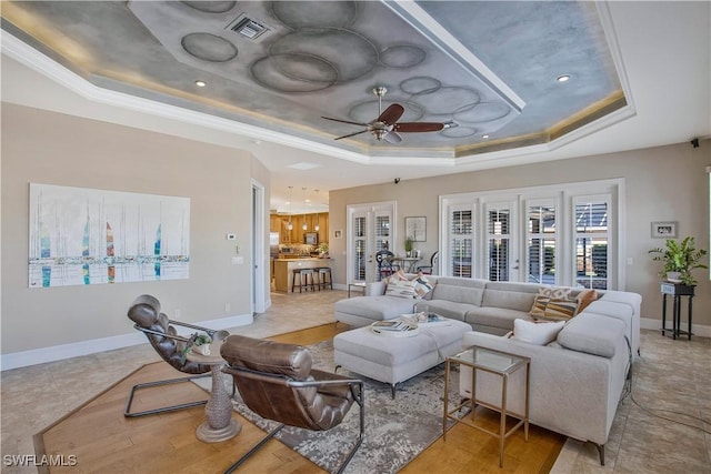 living area featuring a raised ceiling, visible vents, ceiling fan, and baseboards