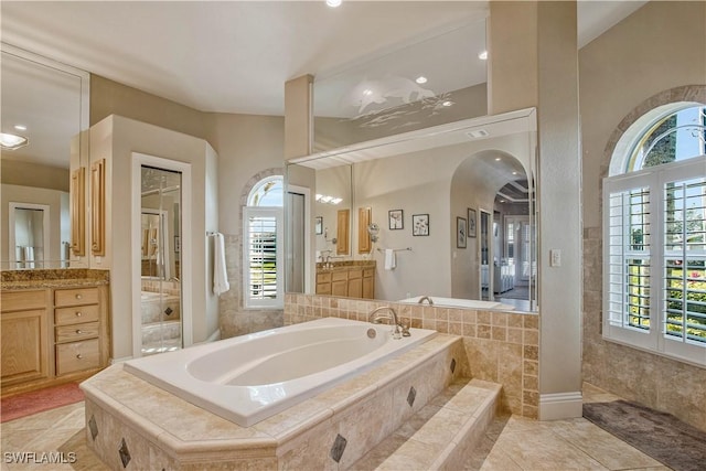 full bath featuring a healthy amount of sunlight, a garden tub, vanity, and tile patterned floors