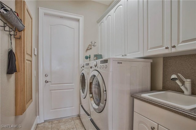 laundry area with washer and dryer, cabinet space, a sink, and light tile patterned flooring