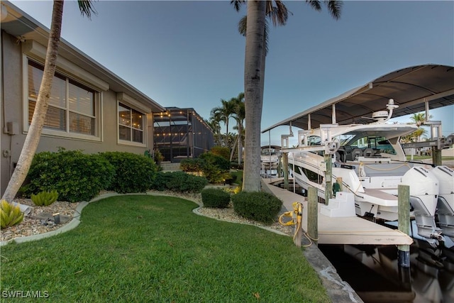 view of dock featuring a lanai, boat lift, and a yard