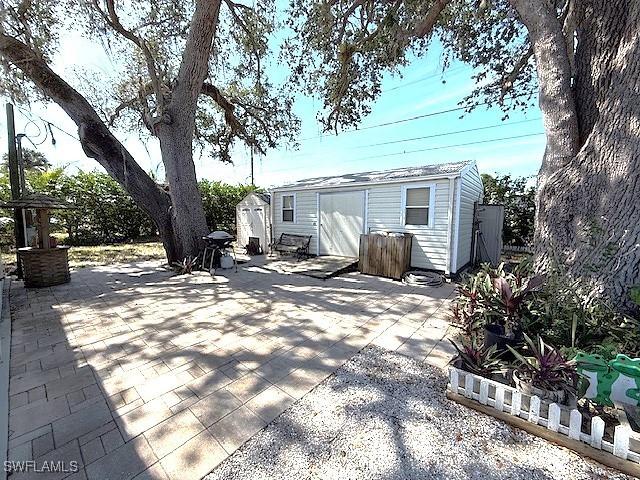 rear view of house featuring a shed, fence, a patio, and an outdoor structure