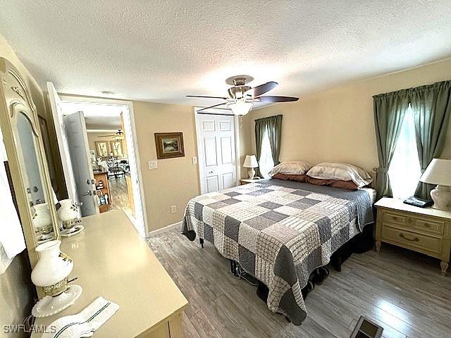 bedroom with dark wood-style flooring, a closet, visible vents, a ceiling fan, and a textured ceiling