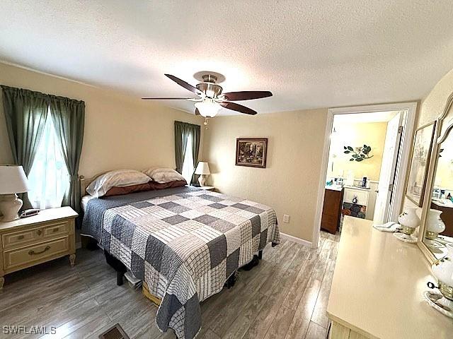 bedroom with dark wood finished floors, a textured ceiling, baseboards, and ceiling fan