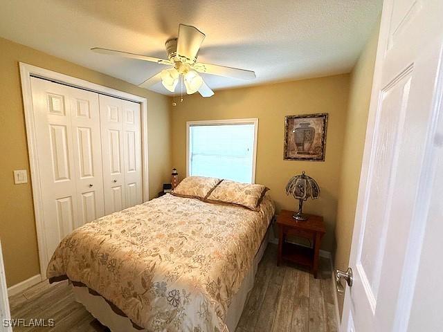 bedroom with a textured ceiling, a closet, wood finished floors, and a ceiling fan