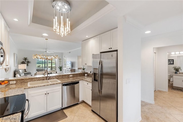 kitchen featuring a notable chandelier, stainless steel appliances, a raised ceiling, white cabinetry, and a sink