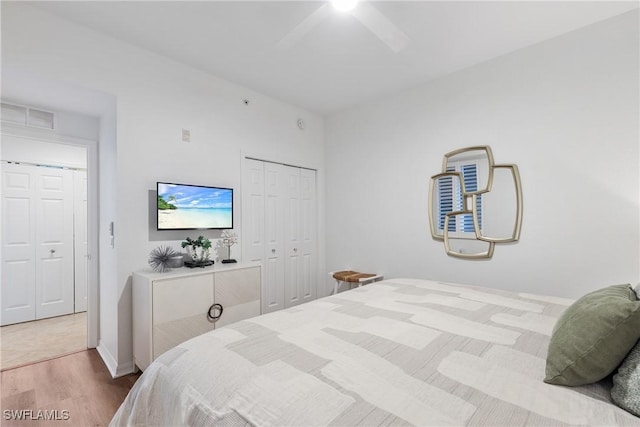 bedroom with a closet, visible vents, ceiling fan, and wood finished floors