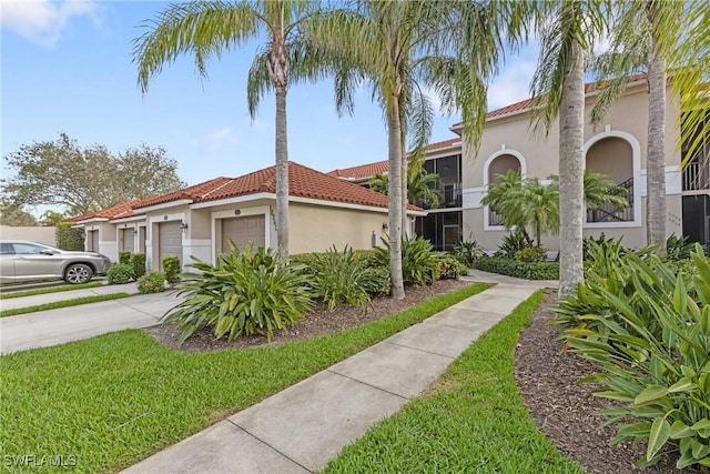 mediterranean / spanish house with a garage, concrete driveway, a tile roof, and stucco siding