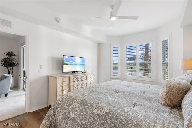 bedroom featuring visible vents, ceiling fan, baseboards, and wood finished floors