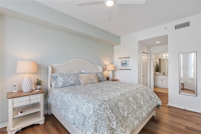 bedroom featuring baseboards, visible vents, a ceiling fan, ensuite bath, and wood finished floors