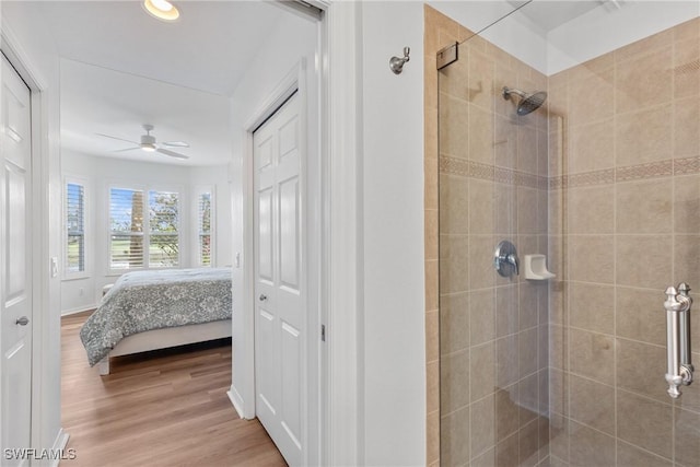 bathroom featuring a ceiling fan, a stall shower, connected bathroom, wood finished floors, and baseboards