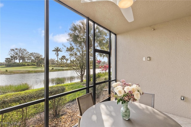 sunroom / solarium with a water view and ceiling fan