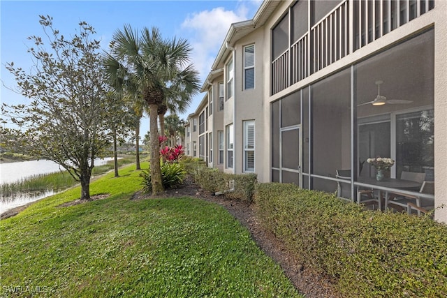 view of yard featuring a sunroom and a water view