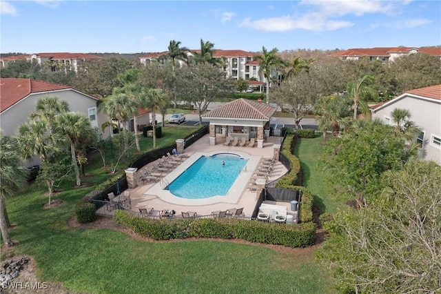 pool with outdoor dry bar, a patio, a lawn, and fence