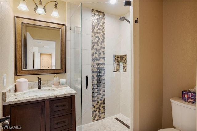 bathroom with visible vents, a shower stall, toilet, and vanity