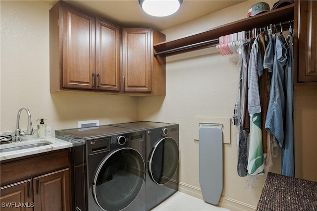 laundry area featuring separate washer and dryer, a sink, cabinet space, and baseboards